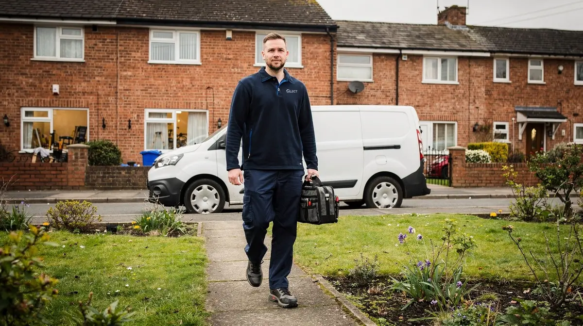 Engineer with a tool bag walking up the front path of a housing association home